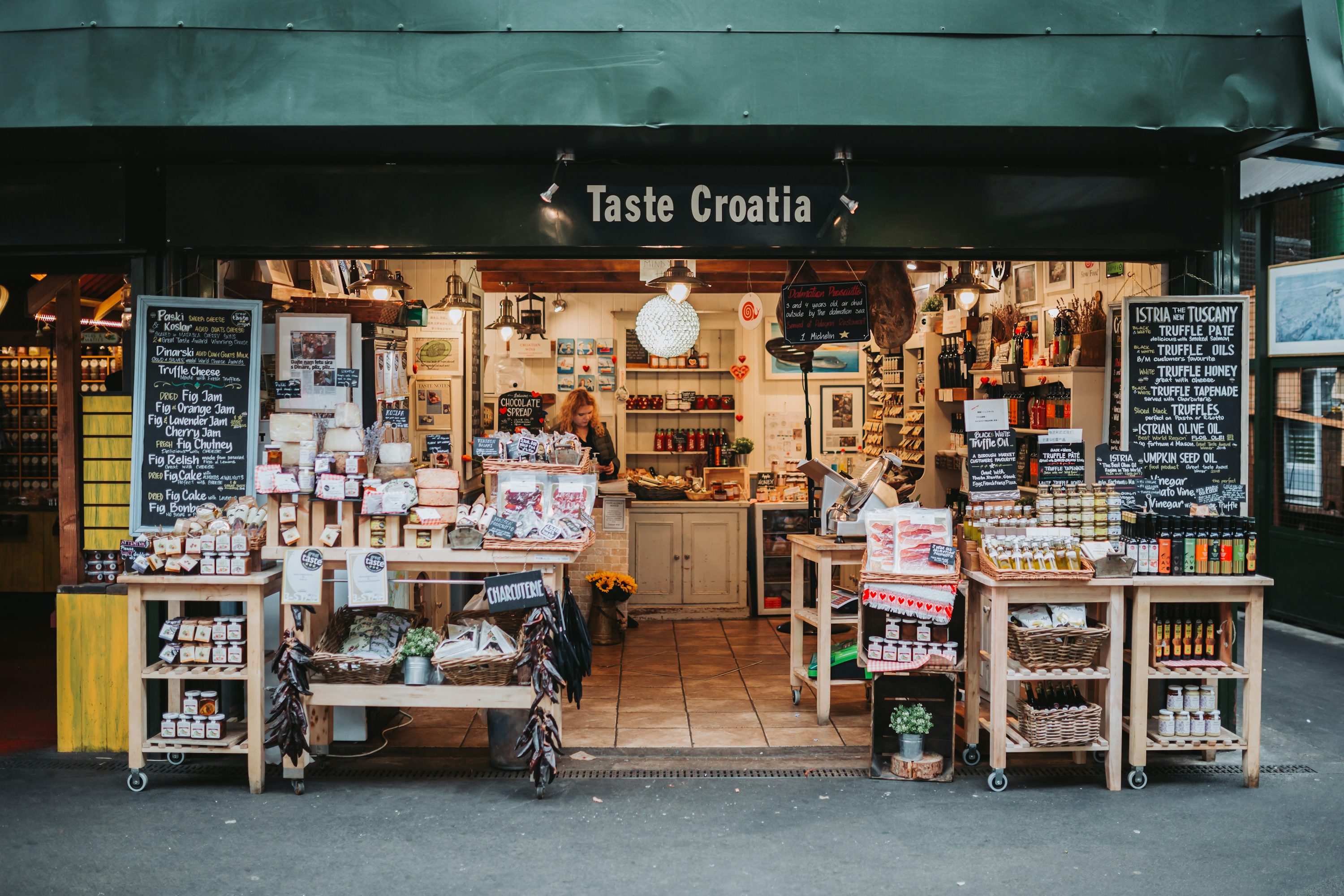 A specialist food stall at Borough Market with preserves, cheese, charcuterie and bottles displayed around an open counter. Archive photograph.